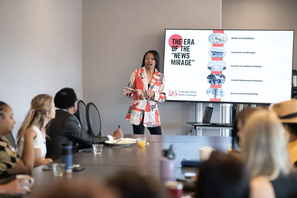 A woman from Colorado Ethnic Media presents a slidedeck in front of a group of people on "The Era of the 'News Mirage'"