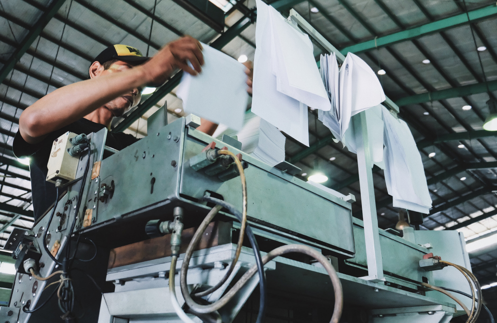 A man standing over a paper printing press